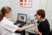 Einer Patientin wird durch eine Arzthelferin der Sehnervenkopf vermessen.