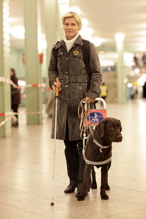 Eine Frau läuft mit ihrem Blindenführhund in einer U-Bahnstation.
