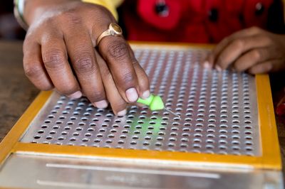 Blindenschrift-Schreibtafel Zwei Hände einer Person nutzen eine Blindenschrift-Schreibtafel.