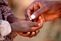 Flussblindheit – Medikamentengabe Die offenen Hände einer Person erhalten eine Tablette aus der Hand einer anderen Person.