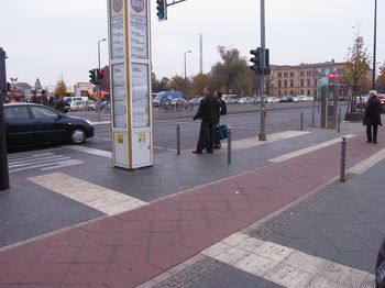 Nahaufnahme von Auffindestreifen quer über den Gehweg zu einer Bushaltestelle