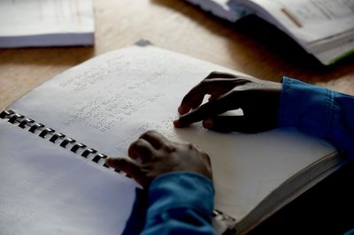 Eine Hand bewegt sich über eine Seite in Brailleschrift.