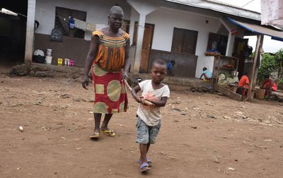Eine afrikanische Frau wird von ihrem Enkel mit Hilfe eines Stocks geführt. Der Junge geht vorneweg, indem er sich am vorderen Ende des Stocks festhält, und die Frau hält sich am hinteren Ende fest, so kann sie Richtungsänderungen und Höhenunterschiede frühzeitig erkennen. Das ist eine typische Art blinde Menschen in Afrika zu führen. 