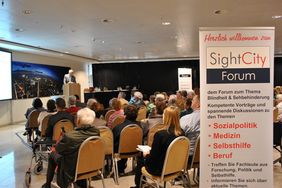 Blick auf einen voll besetzten Vortragsraum. Ein Banner an der rechten Bildseite weist auf das SightCity Forum hin.