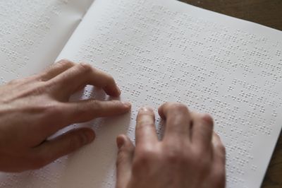 Zwei Hände liegen auf einer Seite in Brailleschrift.